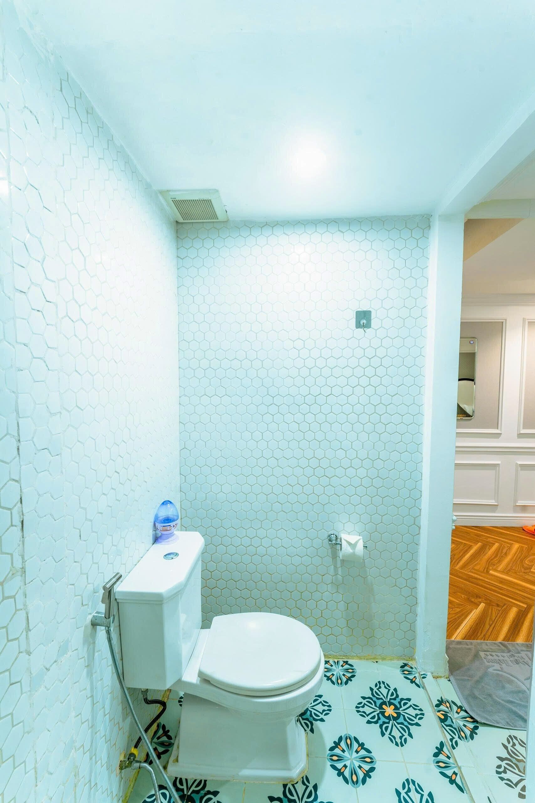 Ein kleines Badezimmer mit Toilette, Warmwasserbereiter und Duschbereich.