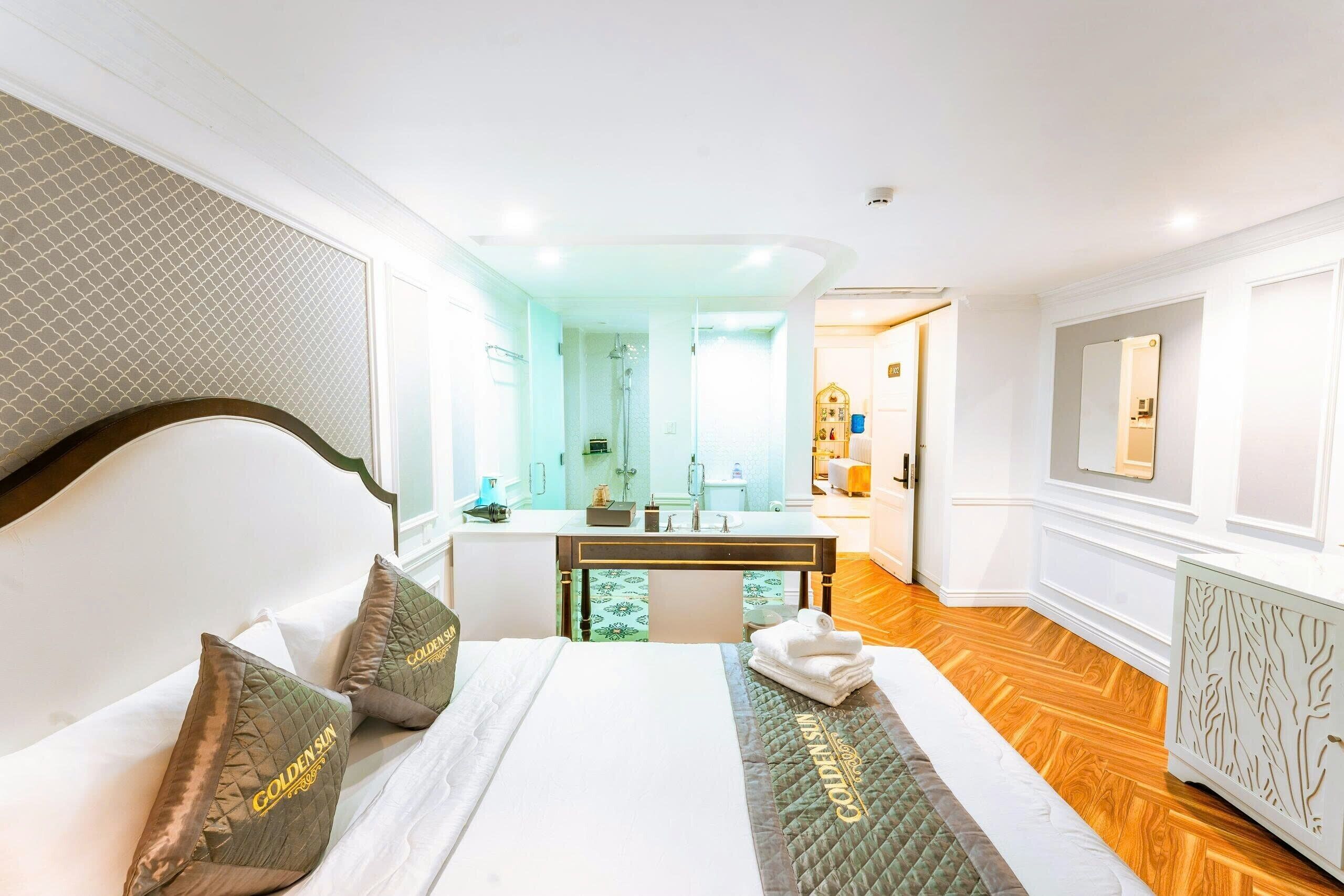 Une chambre d’hôtel avec un lit, un bureau et une salle de bain, visibles à travers une porte ouverte.