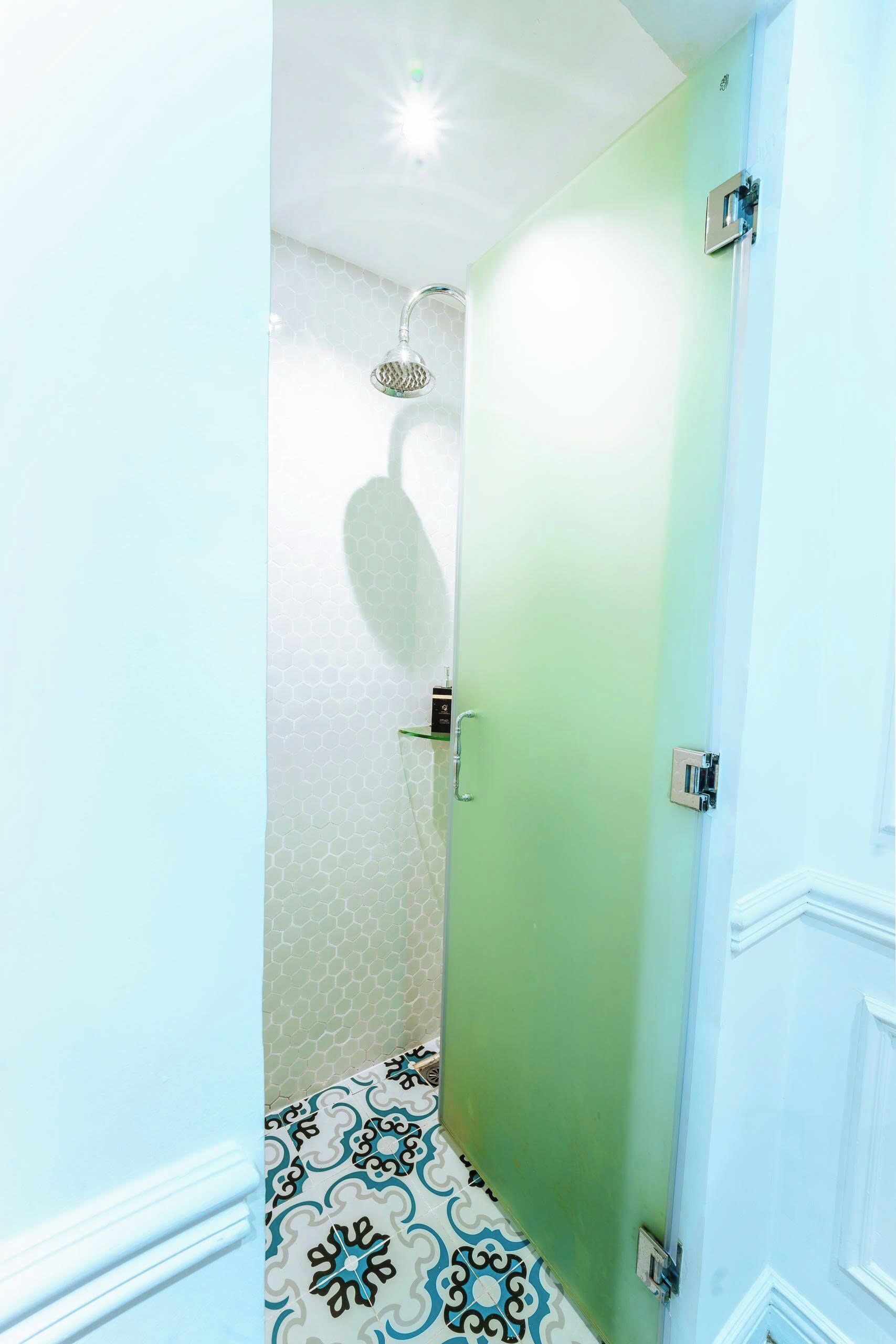 Un pasillo estrecho con zona de ducha, una puerta con picaporte y piso estampado.