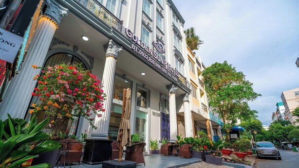 Ein Hotel mit einer klassischen Fassade, großen Säulen und einem Schild mit der Aufschrift 'Golden Sun Hotel'.