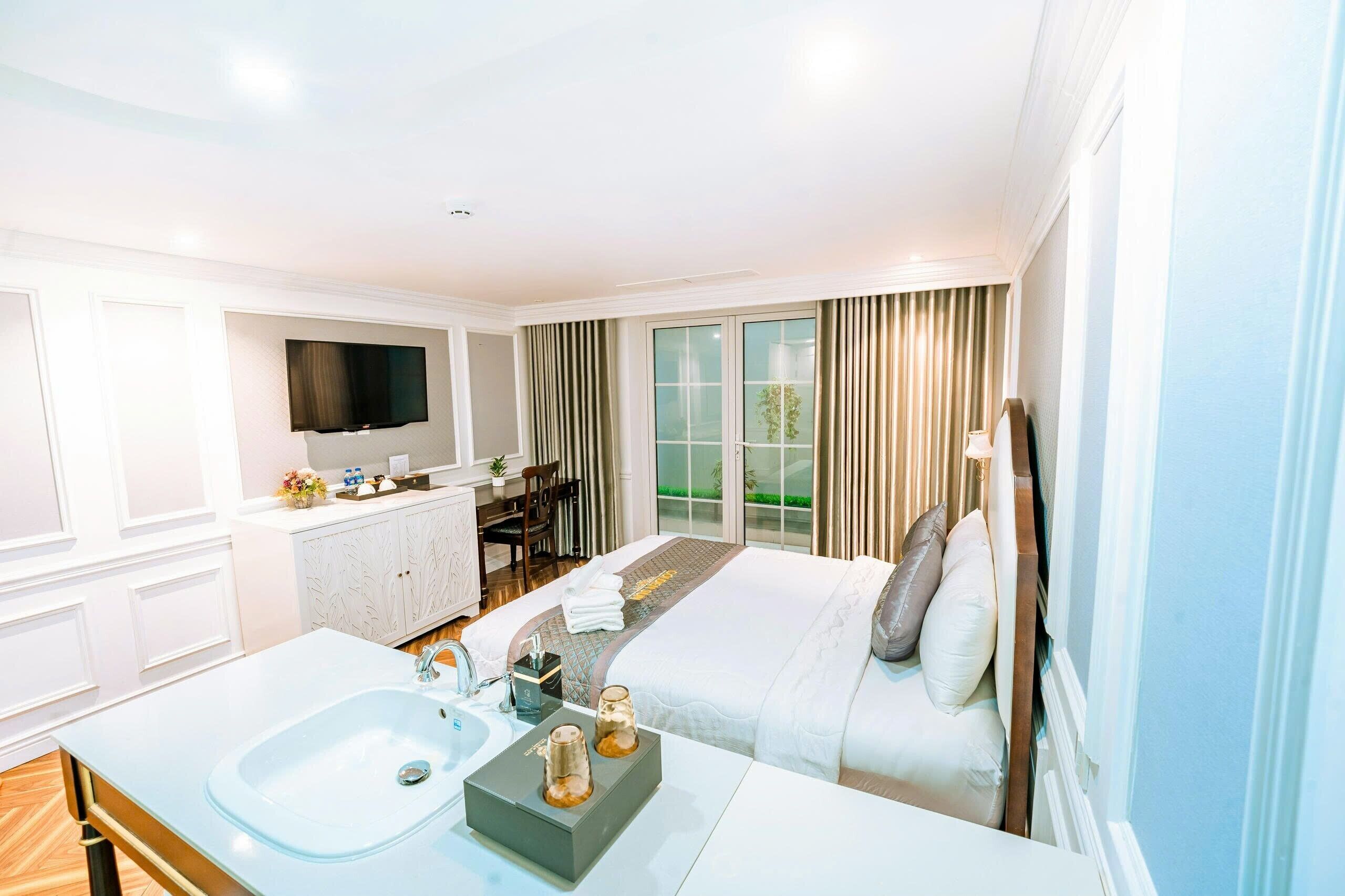 Une chambre d’hôtel dotée d’un grand lit, d’un coin salon, d’une télévision et d’une salle de bain avec un lavabo, et offrant une vue sur l’extérieur.