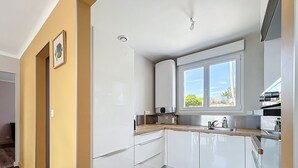 A modern kitchen with white cabinets, a window with a view, and a built-in oven.
