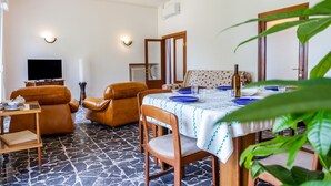Una sala de estar con televisor, sofá y mesa de comedor lista para cuatro comensales.