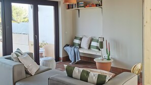 A living room with a sofa, a hanging light fixture, a bookshelf, and a window.