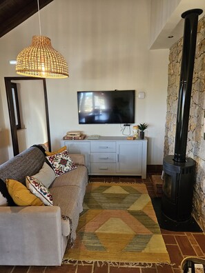 Ein Wohnzimmer mit Sofa, Fernseher, Steinwand und Kamin.