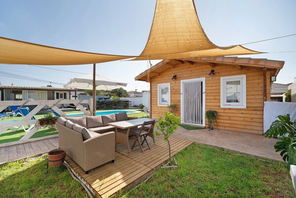 A wooden cabin with a patio, outdoor seating, and a pool.