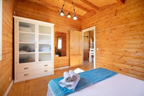 Une pièce aux murs lambrissés, avec un lit, une grande armoire aux portes en verre et un miroir.