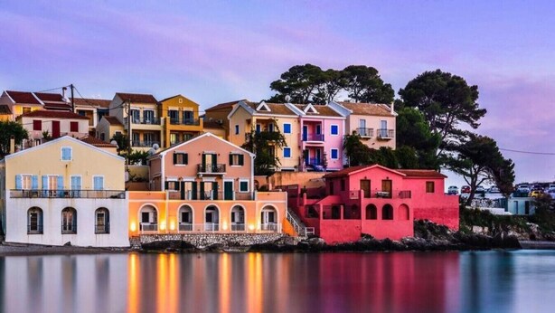 A waterfront property with multiple buildings, including a prominent pink structure and a yellow building with balconies. - THIMARI. Unique location, one min from the beach! (Asos)