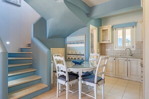 A kitchen with a dining table, chairs, and a staircase.