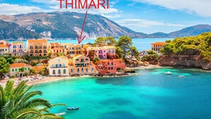 A coastal town with colorful buildings, a clear blue sea, and a mountainous backdrop. - THIMARI. Unique location, one min from the beach! (Asos)