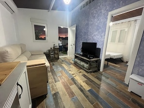 Ein Wohnzimmer mit einer Couch, einem Fernseher und einem Holzkabinett.