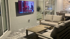 Un salon moderne avec un téléviseur à écran plat fixé au mur, une table basse en bois et un canapé beige.