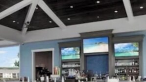 Un espace extérieur aménagé avec des tables et des chaises, un bar doté d’un comptoir et d’étagères, et une vue sur le ciel.