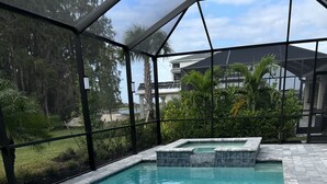 Une piscine rectangulaire, bordée de carreaux et entourée de pierres, le tout intégré dans une structure en verre et en métal.