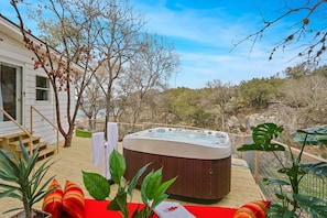 A hot tub on a wooden deck with a view of a natural landscape.