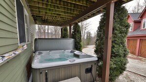 A hot tub with a bench, a wooden pergola, and a house in the background. - The Tanglewood Lodge: Amazing Ski Home For Groups. Hot Tub. Close To Killington Resort! 4 Bedroom Home (Killington)