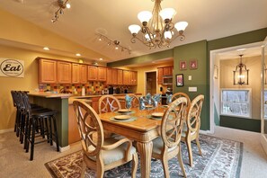 A kitchen with wooden cabinets, a dining table with chairs, and a chandelier.