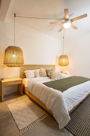 Ein Schlafzimmer mit einem Bett, Nachttischlampen, einem Deckenventilator und einem strukturierten Teppich.
