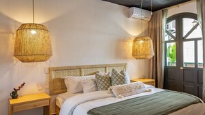 Une chambre à coucher avec un lit en bois, deux tables de chevet, un ventilateur de plafond et une grande fenêtre avec des rideaux.