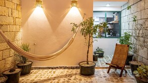 Un espace intérieur accueillant, avec un hamac, des plantes en pot et une chaise en bois.