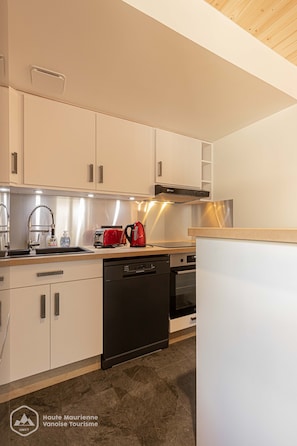 A modern kitchen with white cabinets, stainless steel appliances, and a wooden countertop.