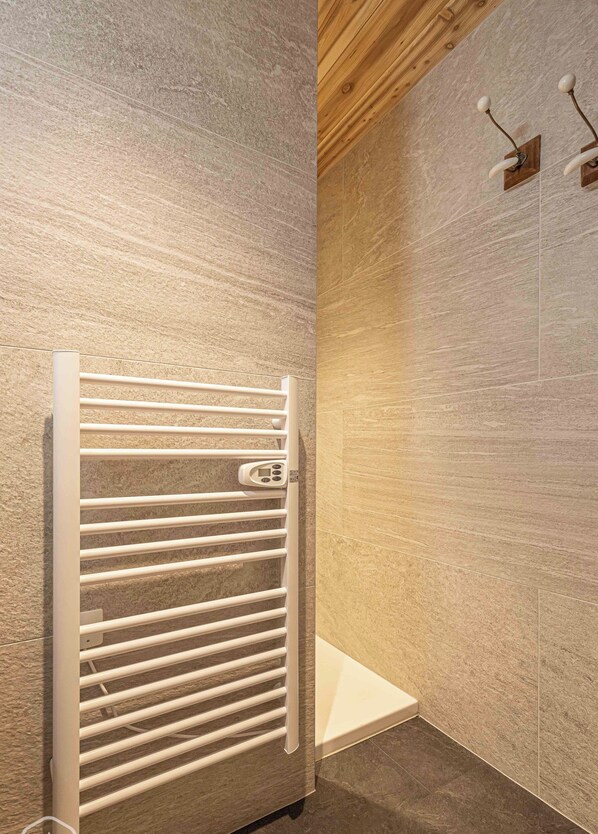 Ein modernes Badezimmer mit integriertem weißen Handtuchwärmer, Holzboden und einer strukturierten Wand.