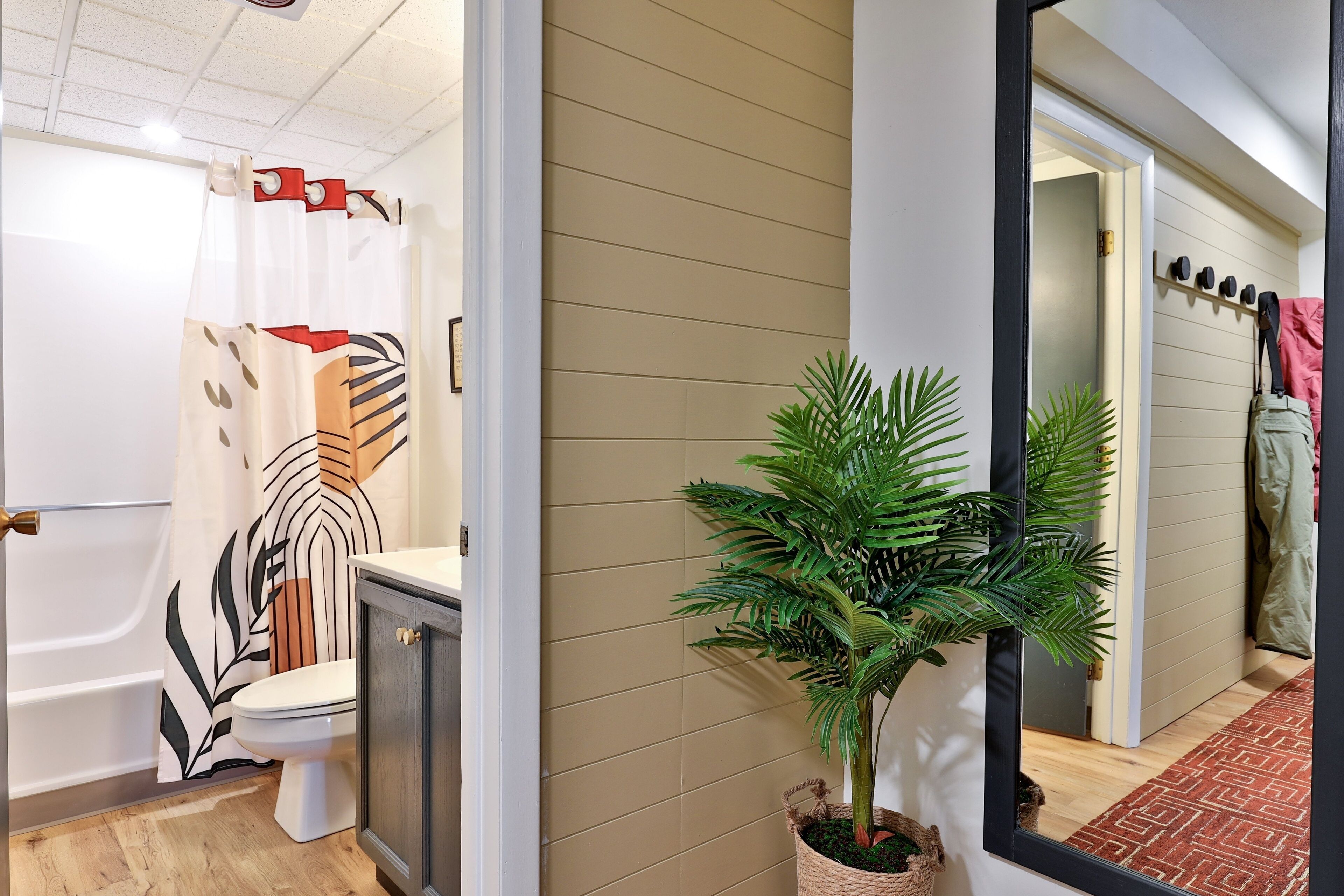 A bathroom with a toilet, shower curtain, and a potted plant.