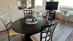 A dining area with a round table, four chairs, a television, and a window with a view. - Ground floor Oceanfront 2 blocks from downtown shopping and eateries (Seaside)