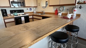 A modern kitchen with a large island, stainless steel appliances, and a clock on the wall. - Ground floor Oceanfront 2 blocks from downtown shopping and eateries (Seaside)