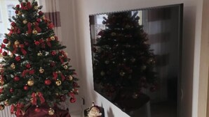 A living room with a Christmas tree, a flat-screen TV, and a fireplace mantel with decorations. - Berg vacation apartment in Annaberg-Buchholz in the heart of the Ore Mountains  (Annaberg-Buchholz)
