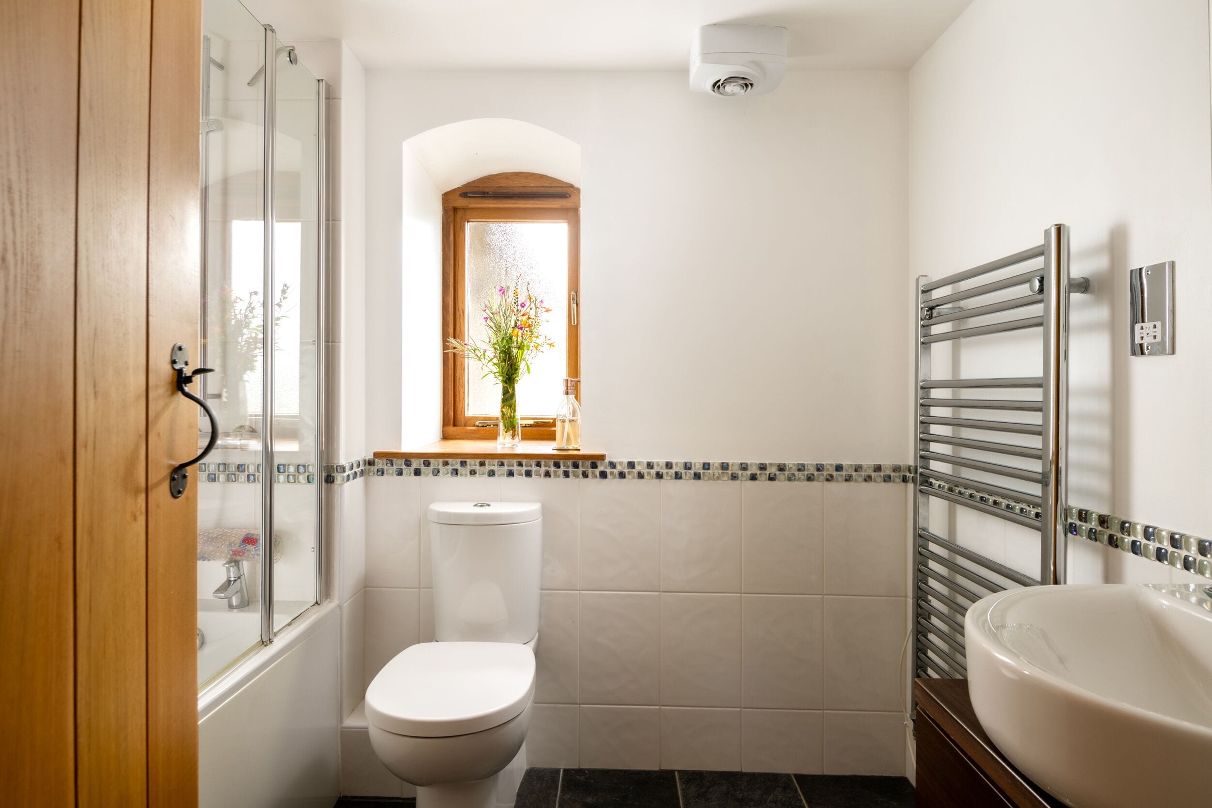 A bathroom with a toilet, a shower, a sink, and a window with a view.