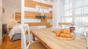 A cozy dining area with a wooden table, chairs, and a wall-mounted plant shelf. - Salty Sea Dog (Tintagel)