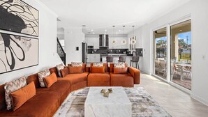 A modern living room with a sectional sofa, a marble coffee table, and a large abstract painting.
