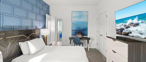 Une chambre d’hôtel avec un grand lit, un bureau, une chaise, une télévision et une vue sur l’océan.