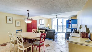 A spacious living area with a dining table, chairs, a sofa, and a TV stand.
