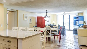A spacious kitchen with a dining area, a red door, and a view of the outdoors.