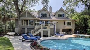 Une maison à deux étages dotée d’une piscine, d’un espace salon extérieur et d’un patio couvert.