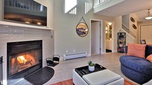 Una sala de estar con chimenea, un televisor de pantalla plana grande, un sofá y una mesa de centro.
