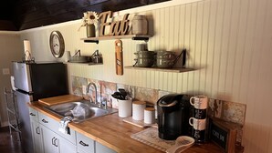 Uma cozinha com bancada de madeira, pia, cafeteira e uma placa que diz 'Coffee Bar'.