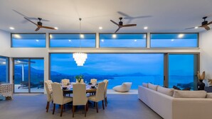 A modern dining area with a view of the sea, large windows, and ceiling fans. - Villa Anushka – Luxury 6BR Koh Samui Villa with Staff, Breakfast & Sea Views (koh samui)