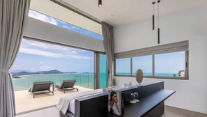 A modern bedroom with a large window, a bed, a desk, and two lounge chairs. - Villa Anushka – Luxury 6BR Koh Samui Villa with Staff, Breakfast & Sea Views (koh samui)