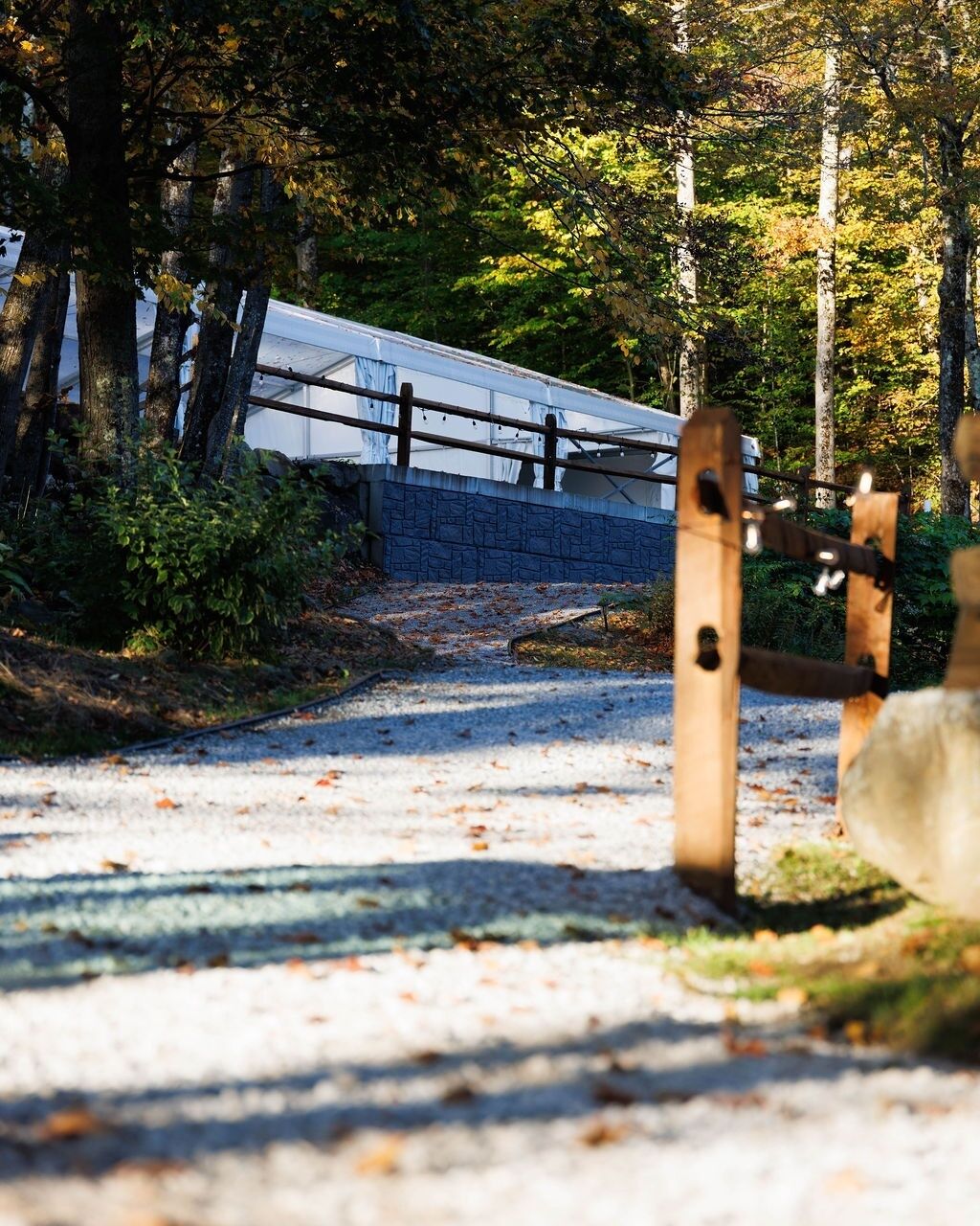A pathway leading to a building with a stone wall and a wooden gate.