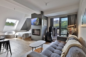 Ein modernes Schlafzimmer im Loft-Stil mit großem Fenster, Kamin und Balkon mit schöner Aussicht.