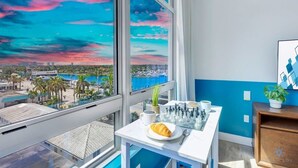 A room with a large window overlooking a cityscape and a table with chess pieces, a croissant, and a cup. - Rooftop Pool & Hot Tub+ Gym+ Near Beach (Hollywood)
