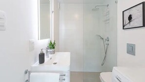 A modern bathroom with a glass-enclosed shower, a white sink with a plant, and a Bosch toilet. - New apartment in Barrio El Golf (Las Condes)