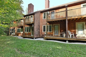 A two-story wooden cabin with a balcony, a chimney, and a deck with outdoor furniture. - Glazebrook by Killington Vacation Rentals (Killington)