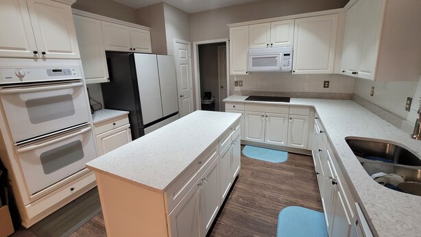A modern kitchen with white cabinetry, a built-in oven, a refrigerator, a microwave, and a stainless steel sink. - Luxury Home 12 Overnight Guests, Wi-Fi for Online Worker, Theme Gold & Diamonds (Woodstock)
