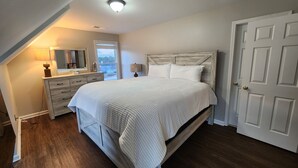 A bedroom with a wooden bed, a dresser, a mirror, and a door. - Luxury Home 12 Overnight Guests, Wi-Fi for Online Worker, Theme Gold & Diamonds (Woodstock)
