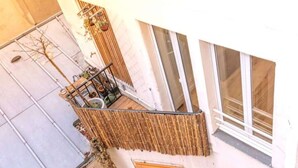 A small balcony with a wooden fence, potted plants, and a window. - Géranimus 199 : Art of Paris (Paris)