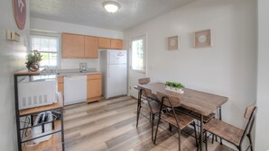 Una cucina moderna con mobili in legno, un frigorifero bianco e un'area pranzo con tavolo e sedie di legno.